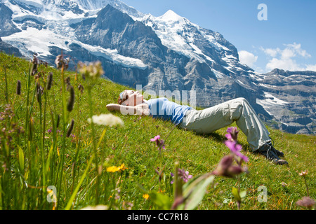 Woman Lying on Grass sur côté montagne, Oberland Bernois, Suisse Banque D'Images