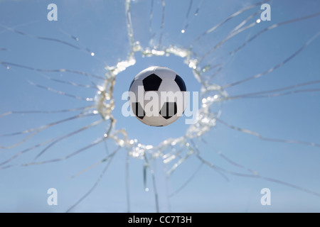 Ballon de soccer Smashing through Window Banque D'Images