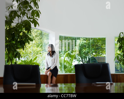 Belle femme d'origine asiatique manager en regardant par la fenêtre dans le bureau. Vue avant, copy space Banque D'Images