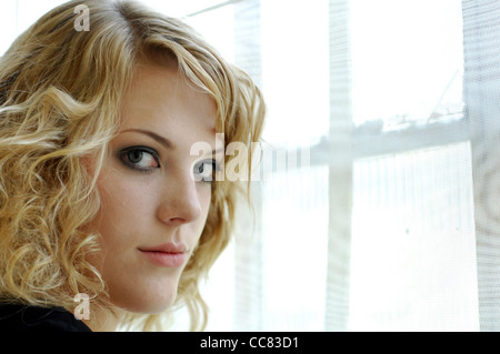 Jeune blonde modèle photographié dans la fenêtre avec un minimum de lumière naturelle maquillage - Image Copyright Ben Pruchnie 2011 Banque D'Images