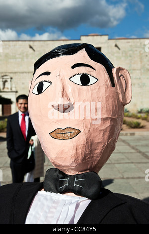 Tête de papier mâché d'une marionnette géante groom figure sur la plaza à l'extérieur de l'église Santo Domingo après une procession de mariage Oaxaca Banque D'Images