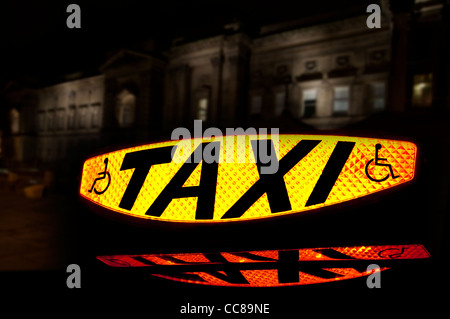 Taxi lumineux montrant le mot Taxi et un symbole pour les personnes handicapées montrent un véhicule accessible en fauteuil roulant Banque D'Images