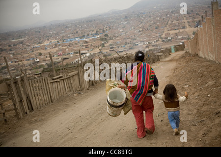 Une femme porte un bébé sur son dos dans un bidonville de Lima, Pérou, Amérique du Sud. Banque D'Images