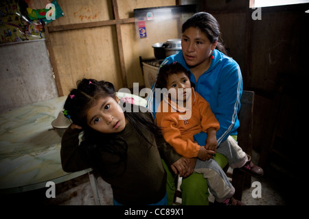 Une famille s'assied à leur table de cuisine dans un bidonville de Lima, Pérou, Amérique du Sud. Banque D'Images