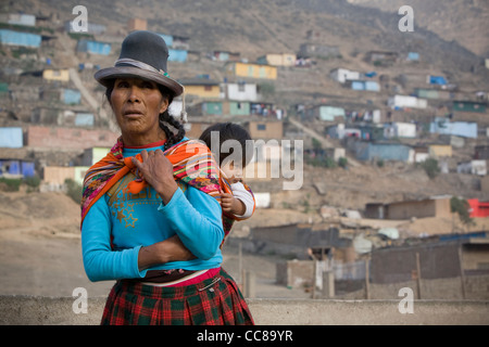 Une femme porte un bébé sur son dos dans un bidonville de Lima, Pérou, Amérique du Sud. Banque D'Images