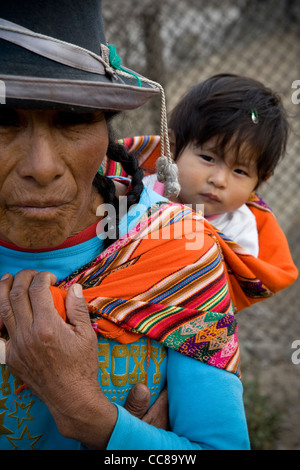 Une femme porte un bébé sur son dos dans un bidonville de Lima, Pérou, Amérique du Sud. Banque D'Images