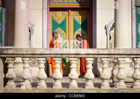 Deux jeunes moines bouddhistes et en saluant la réunion dans un temple, Phnom Penh, Cambodge, Asie,. Vue de côté Banque D'Images