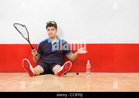 Un jeune joueur de squash déçu tenant une raquette cassée Banque D'Images