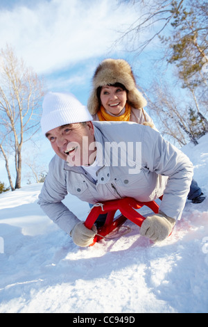 Portrait of happy young couple riding sur un traîneau en hiver Banque D'Images
