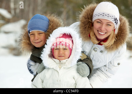 Enfants heureux et leur mère en winterwear looking at camera Banque D'Images