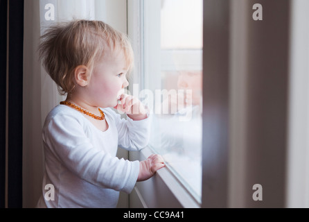 Portrait of baby girl looking out Window Banque D'Images