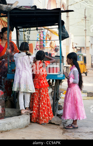 Les jeunes filles indiennes dosa acheter pour le petit-déjeuner à partir d'un panier dans une rue indienne. Puttaparthi, Andhra Pradesh, Inde Banque D'Images