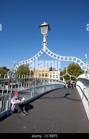 Un sans-abri se trouve sur Ha Penny bridge traversant la rivière Liffey vers Lower Ormond Quay Centre de Dublin en Irlande. Banque D'Images