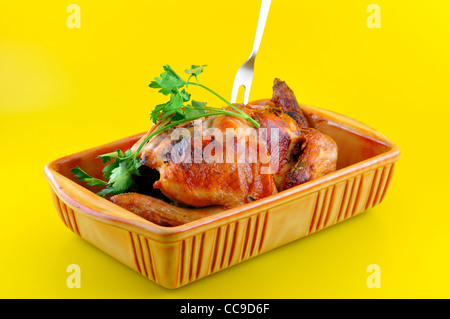 Le poulet cuit dans leur jus dans un bol en céramique avec un brin de persil Banque D'Images