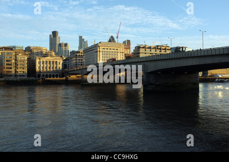 London Bridge enjambe la rivière Thames, comme un matin tôt allume l'architecture de la ville de Londres au-delà. Banque D'Images