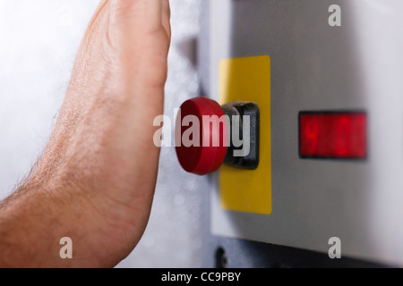 L'homme est l'arrêt d'une machine avec le bouton d'urgence - probablement dans un cas de danger Banque D'Images