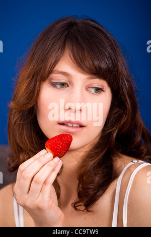 Belle et heureuse jeune femme mangeant une fraise Banque D'Images