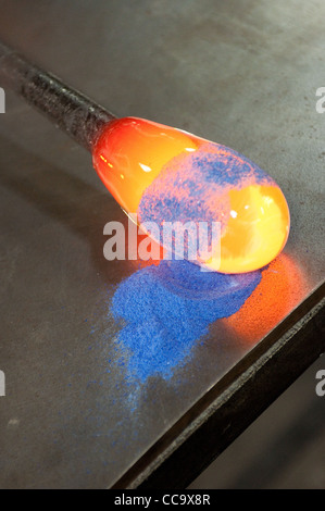 Le verre fondu est enroulé sur le verre pulvérisé sur une table pour ajouter de la couleur Banque D'Images