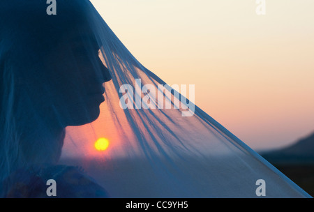 Indian girl et voile au coucher du soleil. Silhouette. L'Andhra Pradesh, Inde Banque D'Images