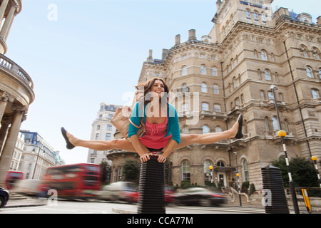 Mid adult woman in pink dress leapfrogging par city street Banque D'Images