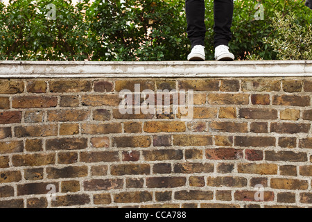 Jeans femme debout sur mur, low section Banque D'Images