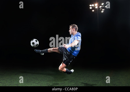 Jeune joueur de football sauter dans l'air pour kick ball Banque D'Images