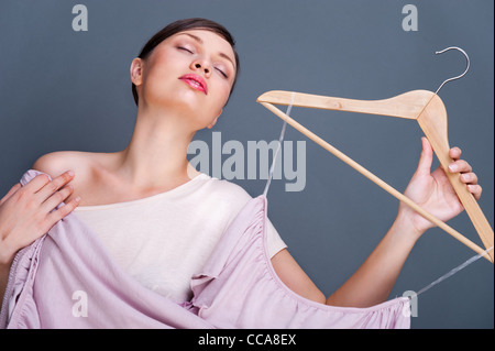 Portrait de jolie femme à la mode d'essayer de nouveaux vêtements. L'affiche de mode tourné à l'intérieur au studio contre fond gris. Banque D'Images