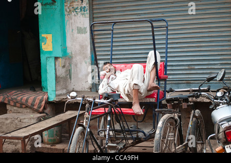 Rickshaw Man sleeping dans son rickshaw, Vrindavan, Uttar Pradesh, Inde Banque D'Images