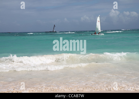 Deux personnes dans un Hobie Cat dans l'eau turquoise des Caraïbes, sable en premier plan Banque D'Images