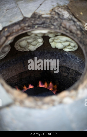 L M Rahman la préparation et la cuisson du pain naan frais dans le four tandoor à Karim's Restaurant, Delhi, Inde Banque D'Images