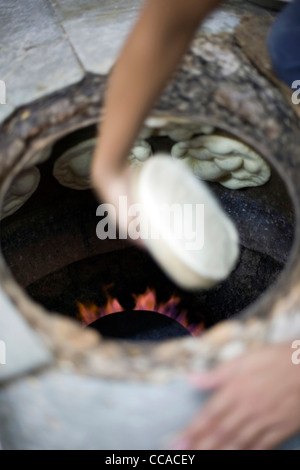 L M Rahman la préparation et la cuisson du pain naan frais dans le four tandoor à Karim's Restaurant, Delhi, Inde Banque D'Images