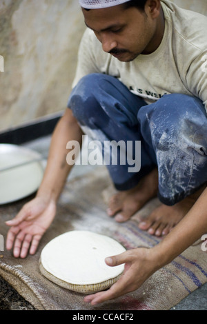 L M Rahman la préparation et la cuisson du pain naan frais dans le four tandoor à Karim's Restaurant, Delhi, Inde Banque D'Images