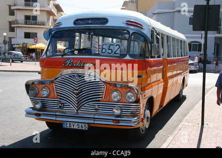 Old fashioned classique Malte bus en couleur traditionnelle de jaune et orange avec toit blanc et chrome calandre. Banque D'Images