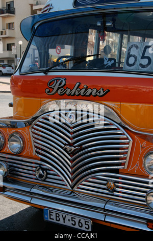 Old fashioned classique Malte bus en couleurs traditionnelles de jaune et orange et blanc avec toit calandre chromée. Banque D'Images