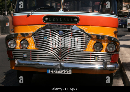 Old fashioned classique Malte bus en couleur traditionnelle de jaune et orange avec toit blanc et chrome calandre. Banque D'Images