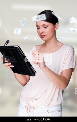 Une femme d'affaires avec des icônes d'affaires flottant autour de sa tête. Portrait de jolie femme travaillant avec son tablet pc Banque D'Images