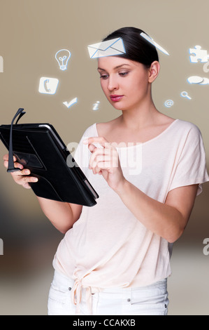 Une femme d'affaires avec des icônes d'affaires flottant autour de sa tête. Portrait de jolie femme travaillant avec son tablet pc Banque D'Images