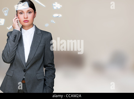 Une femme d'affaires avec des icônes d'affaires voler autour de sa tête. Portrait de jolie femme travaillant avec son téléphone à la recherche à Banque D'Images