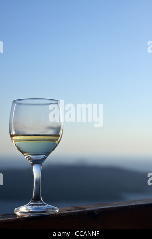 Vue d'un verre de vin blanc sur fond de ciel bleu, à Santorin, en Grèce. Banque D'Images