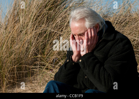 Déprimé senior male sitting on beach Banque D'Images