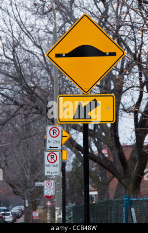 Avertir un bump signe, en haut d'un panneau de flèche dans l'arrière-plan sont les signes d'un parking et d'arbres Banque D'Images
