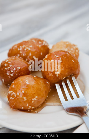 Loukoumades, un grec dessert, servi sur une plaque blanche avec du miel Banque D'Images