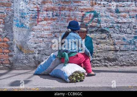 Deux femmes, deux Indiens autochtones andines s'asseoir et parler sur un trottoir dans une petite ville sur la boucle de Quilotoa dans les Andes Banque D'Images