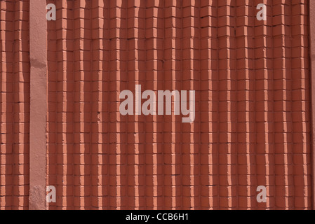 Un résumé en forme géométrique orange - mur de brique rouge qui présente des lignes verticales créées par l'agencement des briques. Banque D'Images