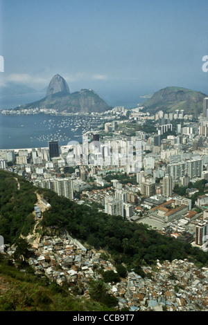 Rio de Janeiro, Brésil. Dona Marta bidonville 'favela' dans le premier plan avec le Santo Ignacio School, immeubles de grande hauteur de Botafogo et le Pain de Sucre derrière ; vue vers l'ouest. Banque D'Images