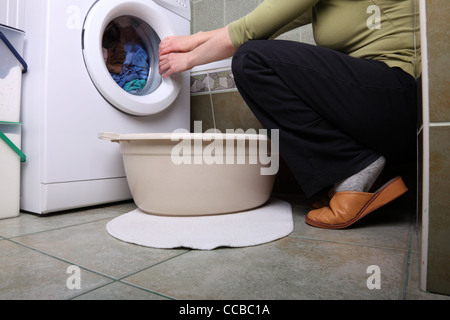 Préparation chargement femme lave-linge dans la salle de bain vêtements dans la machine à laver Banque D'Images