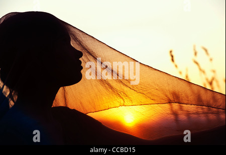 Indian girl et voile au coucher du soleil. Silhouette. L'Andhra Pradesh, Inde Banque D'Images