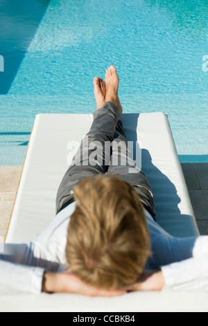 Man relaxing on lounge chair à côté piscine Banque D'Images