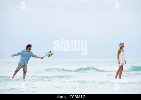 Couple standing in mer, femme marche loin de l'homme tel qu'il est titulaire d'un bouquet Banque D'Images