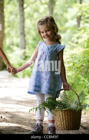 Girl carrying basket remplie de frondes de fougère Banque D'Images